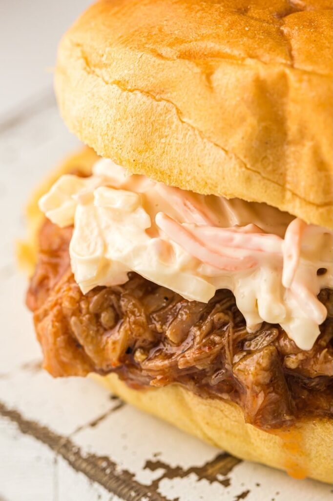 Close-up of a pulled pork sandwich made with tender BBQ Instant Pot pulled pork topped with creamy coleslaw on a soft bun.