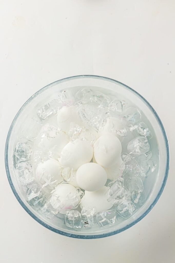 Hard-boiled eggs sitting in a bowl of ice water to cool after cooking in the Instant Pot.
