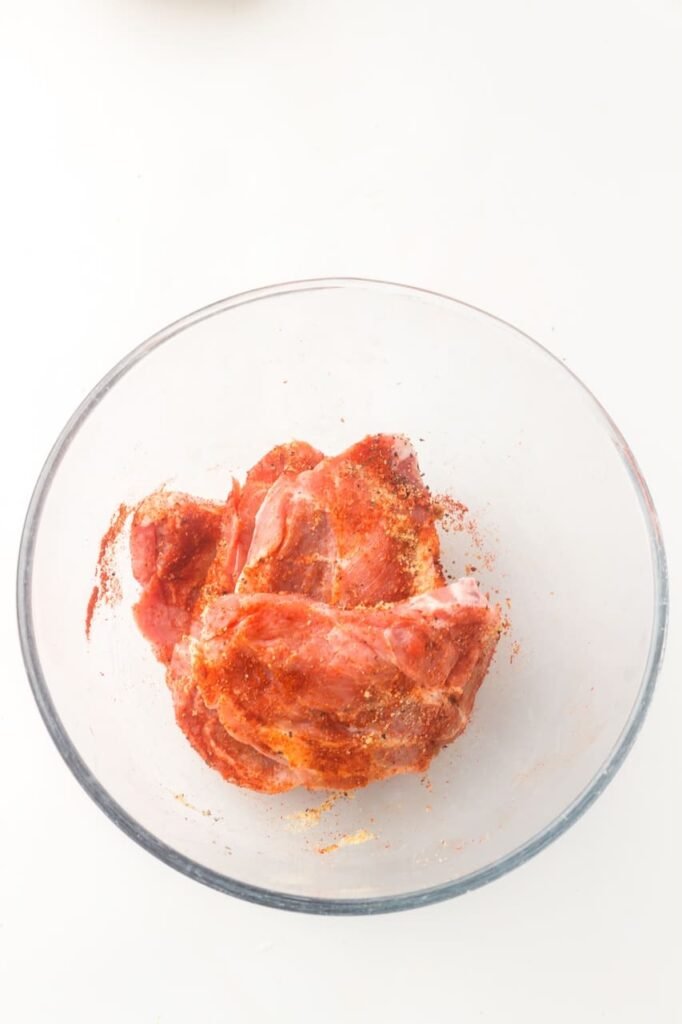 Shoulder steaks coated in a smoked paprika spice rub inside a glass bowl, ready to cook.