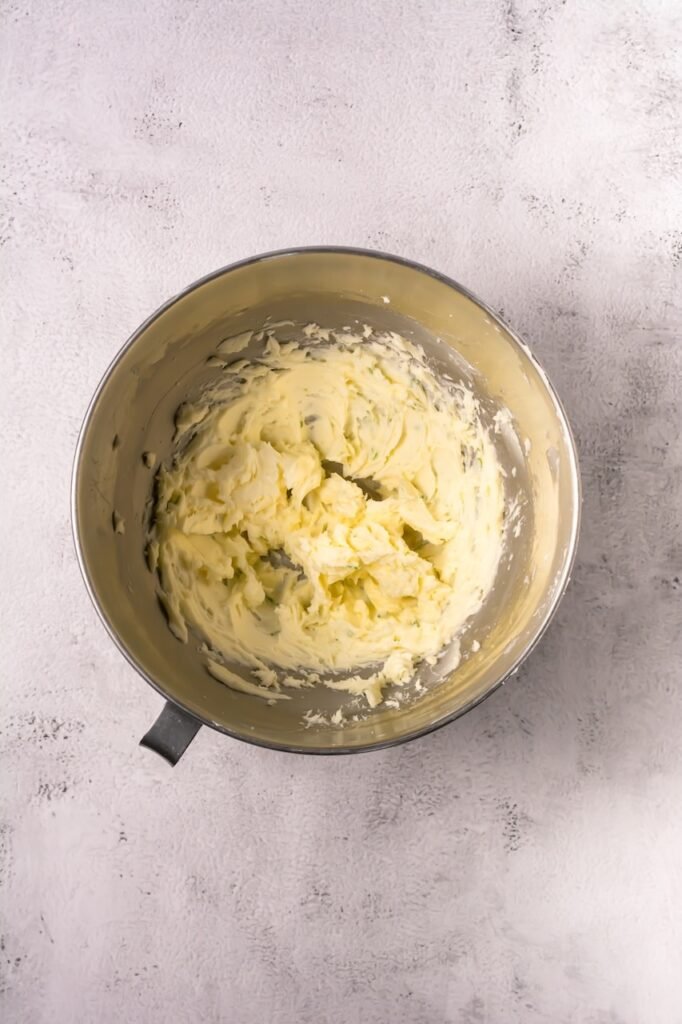 Creamy lime buttercream frosting mixed in a stand mixer bowl for topping coconut lime cookies.