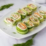 Plated smoked salmon cucumber rolls made with thin cucumber ribbons, cream cheese, smoked salmon, and fresh dill, sliced into bite-size appetizer pinwheels.