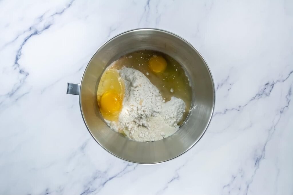 Mixing bowl with eggs, oil, and dry ingredients ready to be combined into dough.