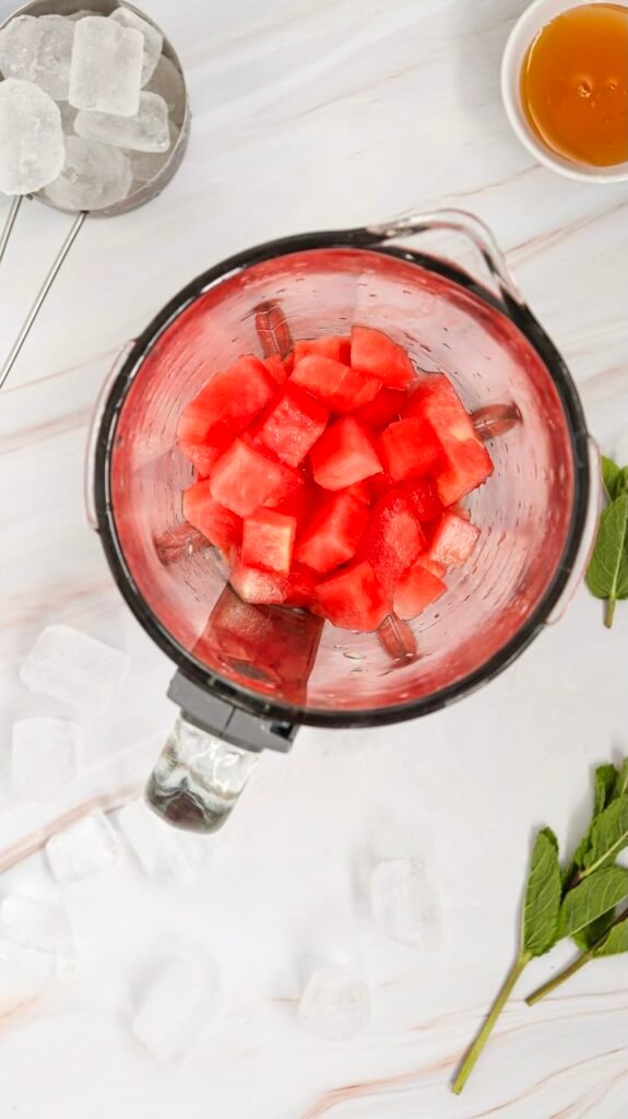 Top view of a blender filled with cubed watermelon, showing the first step of blending watermelon for a homemade slushie