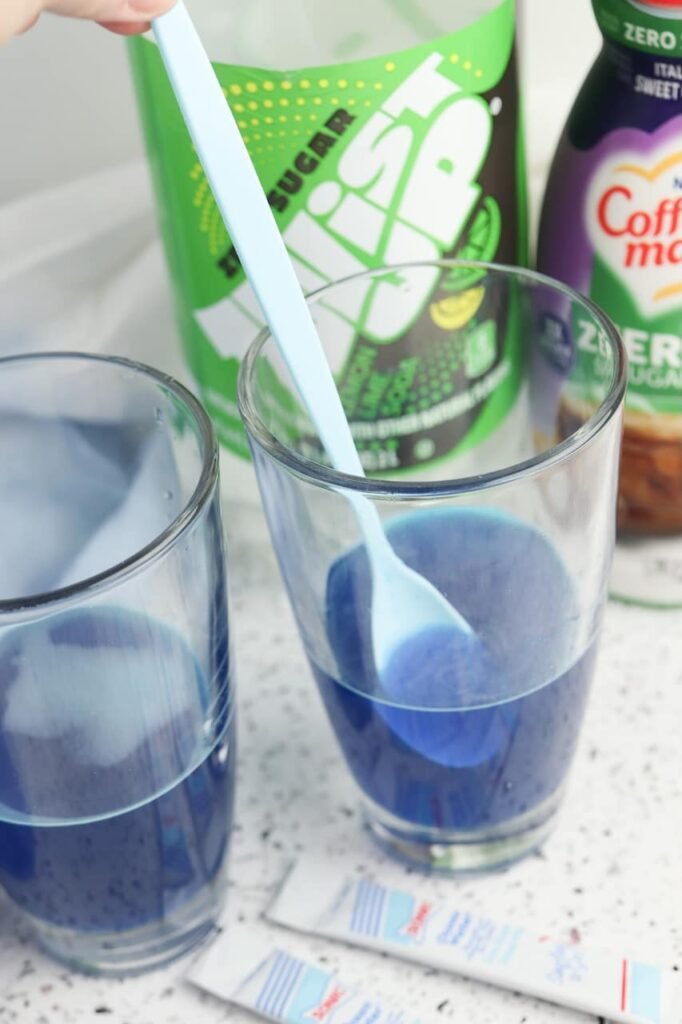 Two glasses filled with blue Ocean Water drink and crushed ice, showing the step before adding soda and sweet cream