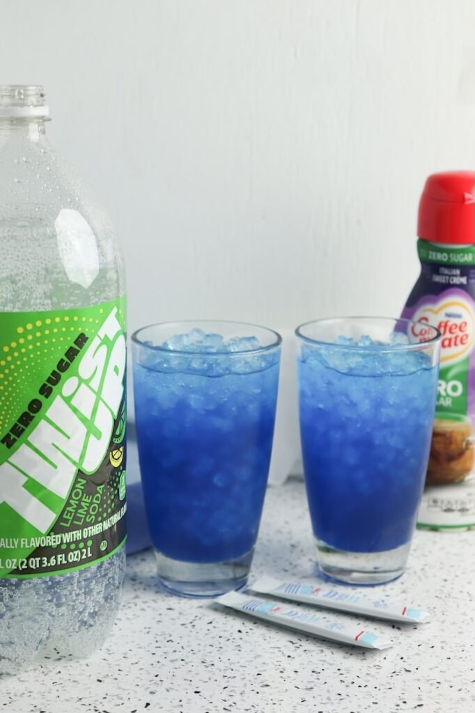 Two glasses filled with ice, with lemon lime soda and sweet cream coffee creamer in the background