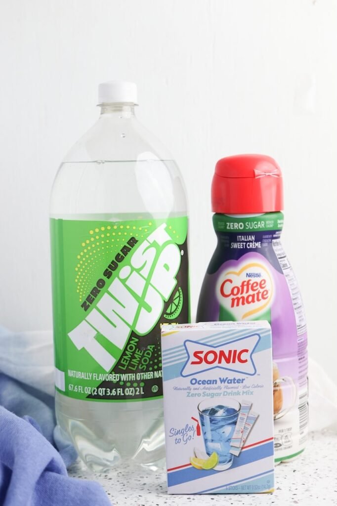Ingredients for Dirty Ocean Water including lemon-lime soda, sweet cream coffee creamer, and Ocean Water drink mix displayed on a countertop