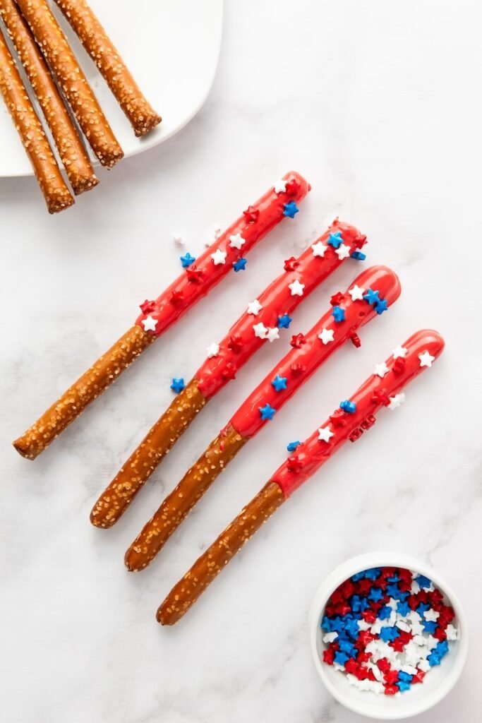 Finished snack dipped in red candy coating and decorated with red, white, and blue sprinkles, arranged on a surface.