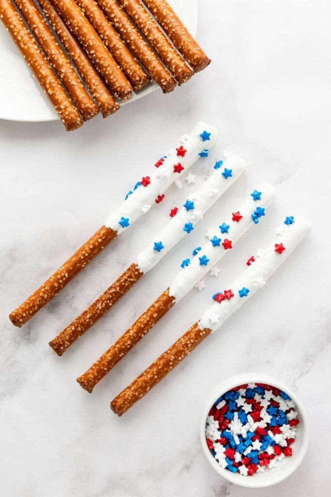 Close-up of coated in white candy and decorated with red and blue star sprinkles, partially visible in a stylized background.