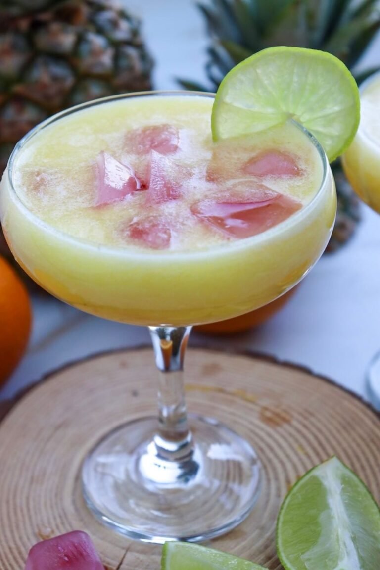 Pineapple margarita mocktail served over ice in a glass with a lime slice garnish, showing a refreshing tropical drink.