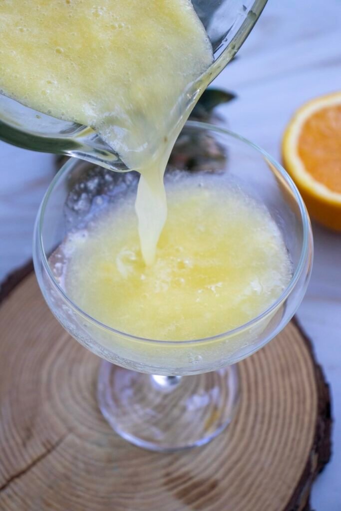 Pouring blended mixture into a glass, showing the smooth texture of a summer drink.