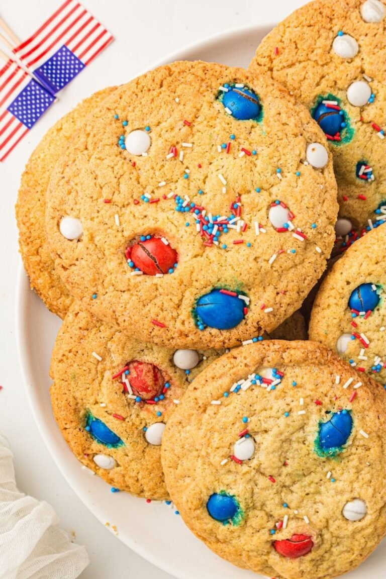 Plate of soft and chewy 4th of July cookies topped with red, white, and blue M&Ms and patriotic sprinkles. The homemade patriotic cookies have golden edges, soft bakery-style centers, and festive summer colors perfect for Independence Day parties and summer dessert tables.