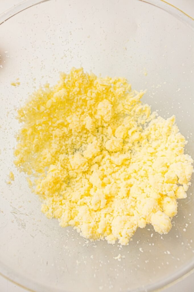 Partially mixed butter and sugar in a clear glass bowl before fully creaming cupcake batter.