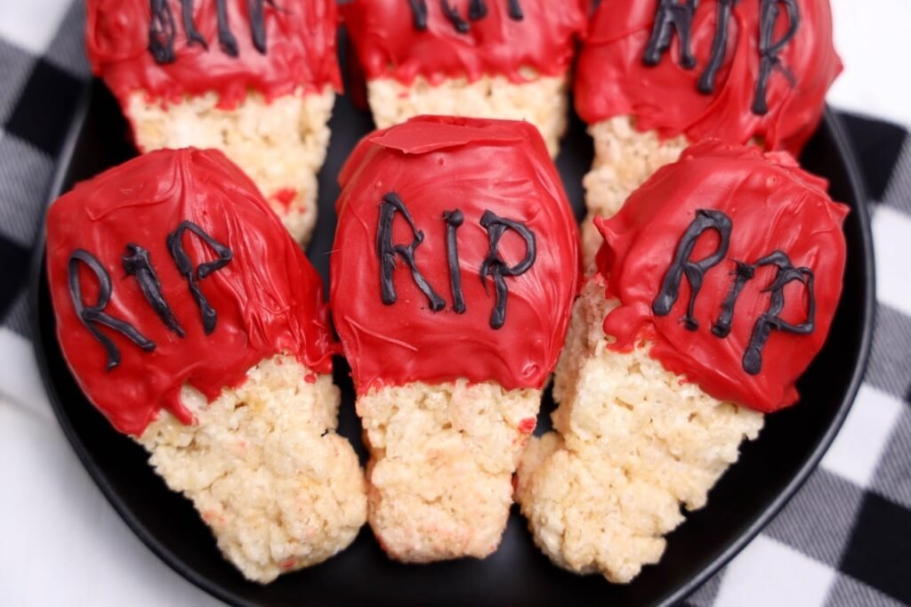 No bake dessert decorated with red candy melt gravestones and black "RIP" lettering arranged on a black serving plate.