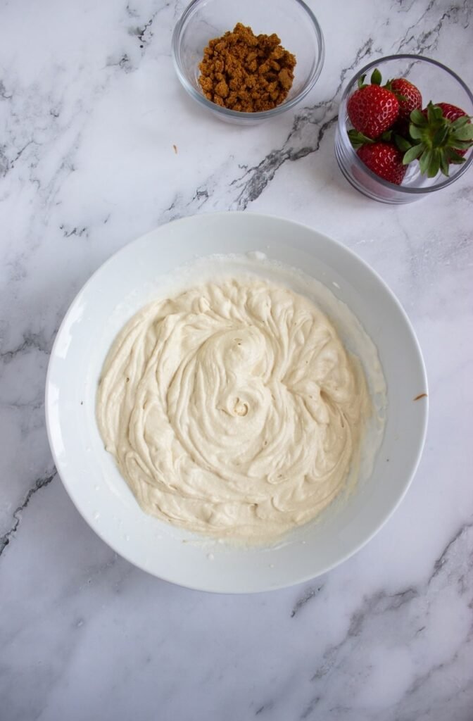 Freshly whipped heavy cream in a white mixing bowl, beaten until soft peaks form during the process of making homemade Biscoff whipped cream. The whipped cream has a light, airy texture and serves as the creamy base before mixing in the Biscoff spread.